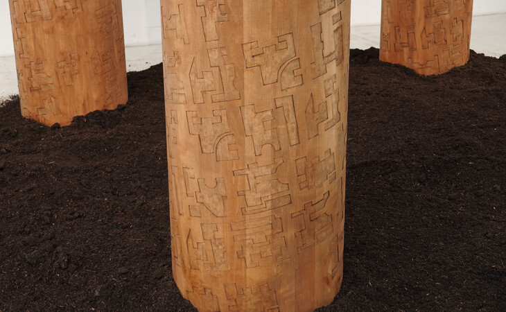 Mit Erde bedeckter Boden aus dem drei Holzsäulen ragen.